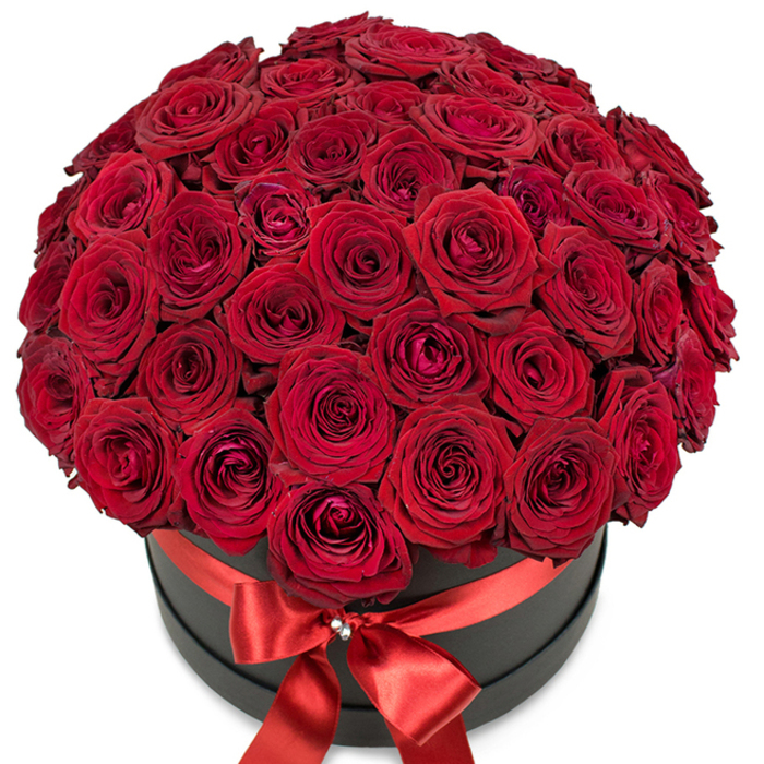 Bathed in bright, diffuse light, a breath-taking composition of premium red roses fills a modern hat box with drama and sophistication. Each bloom, flawlessly shaped and saturated with a rich, velvety crimson, stands as a testament to passionate affection and enduring love. The dense, perfectly domed bouquet is masterfully arranged by Clerkenwell Flowers, its layered petals unfolding outwards to create an inviting tapestry of texture and depth. Subtle shading between petals and blooms gives the arrangement a sense of sculptural luxuriance, reminiscent of the refined aesthetics found in Clerkenwell's art galleries and design studios. The matte-black round box acts as a bold yet understated base, its cool surface contrasted by a radiant scarlet satin ribbon wrapped around the upper edge-a bow immaculately tied at the front center, highlighted by a petite crystal or rhinestone embellishment gleaming quietly, much like the polished windows along Rosebery Avenue. Photographed on a pure white background, the bouquet's reds and blacks are heightened for maximum visual impact. This arrangement is designed for moments of romance and celebration, making it ideal for anniversaries, Valentine's Day, or when only the most opulent gesture will suffice-reflecting the fine taste and creative vibrancy synonymous with central Clerkenwell.