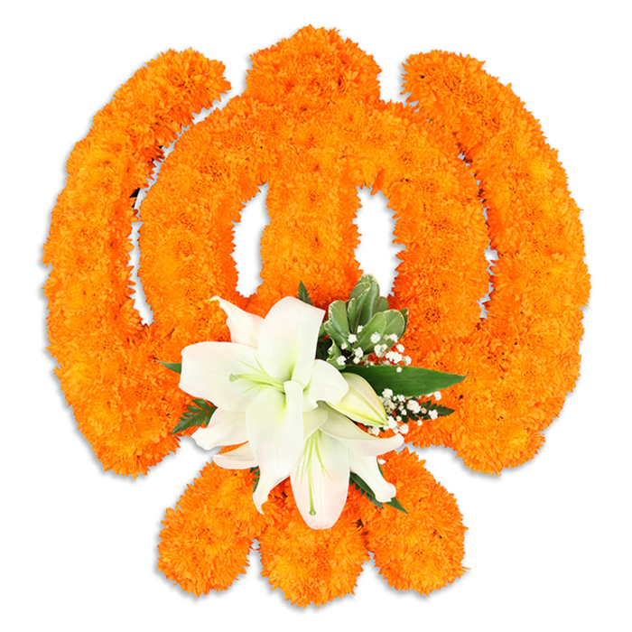 A meticulously crafted floral Ik Onkar symbol occupies the centre of a stark white field, its graceful form assembled from a dense carpet of vivid orange marigold heads. The elements of the Ik Onkar are carefully modelled: the vertical '1' (Ek) reads as a compact column of marigold texture, crescent-like extensions curve away with confident orange fullness, and the finishing dot or bindi is suggested by a small, concentrated cluster-altogether creating a recognisable silhouette that glows against the neutral background. At the lower centre of the marigold composition, a subdued cluster of immaculate white lilies provides a quiet counterpoint: two substantial lilies open into gentle cups, their petals slightly rolled back to reveal soft green-and-yellow stamens, while several tight buds nestle close, promising new blooms. Fine sprays of baby's breath float like tiny stars among the foliage, and lush pointed leaves lend structure and a fresh green edge that keeps the bright orange from feeling flat. A delicate shadow beneath the piece confirms it is a physical, freestanding creation rather than a flat motif, crafted to be placed on a ceremonial table or displayed at a community gathering. The texture is tactile and inviting-marigolds' cushiony heads against the silky lily petals-and the overall mood balances celebration with quiet devotion. Imagining this on a sunlit morning in Clerkenwell, perhaps near St John's Square or Exmouth Market, its colours would read as both traditional and joyful, marking Vaisakhi or Guru Nanak Jayanti with floral reverence and local craftsmanship.