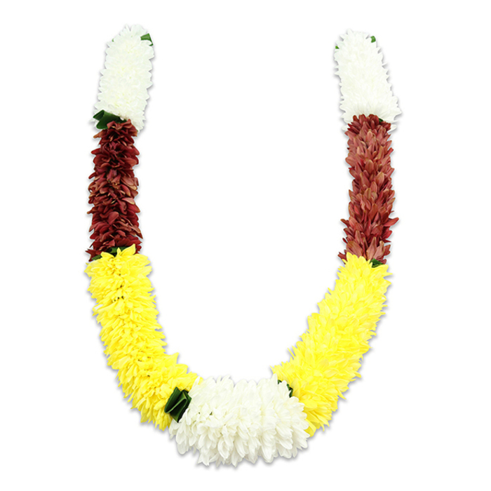 A vividly coloured U-shaped garland sits against a pure white background, its soft shadow articulating each dense band of petals. The top of each arm begins with a compact, cylindrical swathe of creamy white blooms-airy yet plush like small chrysanthemums-followed by a tight, intricately arranged section of maroon or reddish-brown that gives the upper curve weight and solemnity. The dominant lower arms unfold into a long, exuberant sweep of bright yellow, the petals layered to create a full, cushiony appearance reminiscent of marigold garlands used at celebratory gatherings. At the base, where the yellow arcs converge, a generous cluster of pure white chrysanthemum-like flowers forms a strong central focal point, subtly set off by small, dark green leaf motifs that mark the transitions and provide a cool visual pause. The artificial fabric petals catch light in soft highlights, revealing the thousands of tiny shapes and the artisan skill that arranged them; the result is ceremonial without fragility. This mala reads as both festive and reverent-suited to Hindu pooja, temple offerings, weddings or Diwali décor-and one can easily imagine it draped in a Clerkenwell home near St John's Square or carried at a local community celebration. The colours bear traditional meaning-purity, prosperity and devotion-and the piece is designed for repeated ceremonial use while preserving the tactile, enveloping quality of fresh flowers.