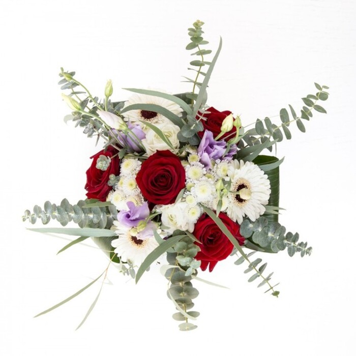 As an experienced florist working daily within the creative bustle of Clerkenwell, I see this bouquet as an embodiment of subtle luxury and genuine intent. Set in a gleaming glass vase, robust deep red roses anchor the design with their velvety depth, symbolising lasting affection felt on the historic streets of Farringdon. Their classic splendour is perfectly echoed by broad, snowy gerbera daisies-each one radiant and luminous, with their dark mocha centres mirroring the artisan coffee found by St John's Gate. Delicate lisianthus blooms, shaded in the lightest touches of lavender, drift thoughtfully through the arrangement, their forms ranging from tightly curled buds to graceful open petals-each stage suggesting stories unfolding along Exmouth Market. Soft, cloud-like clusters of white filler flowers add gentle movement and invite the eye to linger, while round, aromatic eucalyptus leaves bring a cool, silvery freshness reminiscent of Clerkenwell Green's calm. The exterior ring of wide, glossy foliage at the bouquet's base gives shape and polish, ensuring every element feels curated and complete. Submerged stems gleam in clear water, a testament to the arrangement's freshness and the signature care of Clerkenwell Flowers. Whether expressing sympathy, celebrating a cherished milestone, or simply brightening a home or workspace, this bouquet radiates understated elegance and neighbourhood charm-crafted with the same trust and artistry that define our local floral tradition.