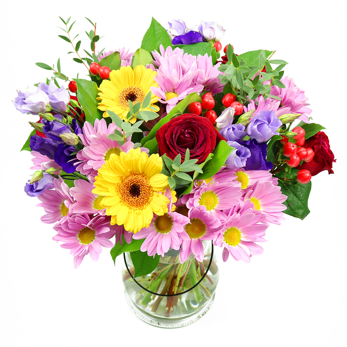 In this image, a lush, mixed bouquet brimming with colour is arranged in a simple clear glass vase, set before a bright white background so every stem and petal can be easily appreciated. Deep red roses lie at the centre, their tightly layered, velvety petals drawing the eye inward and giving the design a sense of classic romance that would suit anything from an anniversary dinner in Clerkenwell to a thoughtful thank-you for a local neighbour. Around them, large yellow gerbera daisies stand proudly, each bloom with a dark, warm-toned centre that adds contrast and a sunburst effect, as if echoing the lively energy of nearby Exmouth Market. Soft pink daisies or chrysanthemums fan out generously, their multi-petalled heads and petite yellow cores creating a halo of pastel colour that softens and expands the bouquet. Woven amongst this are graceful stems of lisianthus in shades of purple and lavender, the bell-shaped, ruffled flowers adding gentle movement and a cool, calming note that balances the warmer hues. Small clusters of round, cherry-red hypericum berries punctuate the arrangement, giving it tiny bursts of texture and a contemporary flourish. Surrounding and supporting all of this is a rich variety of greenery-broad, dark leaves and slender, lighter green sprigs-that evoke a fresh, garden-like feel despite the careful, professional structure. Through the transparent vase, the buyer can see the cleanly cut stems submerged in clear water, a subtle sign of freshness and care. The bouquet feels abundant and welcoming, ideal for brightening a Clerkenwell workspace, celebrating a milestone, or simply bringing a colourful focal point into a modern apartment near Farringdon Road.