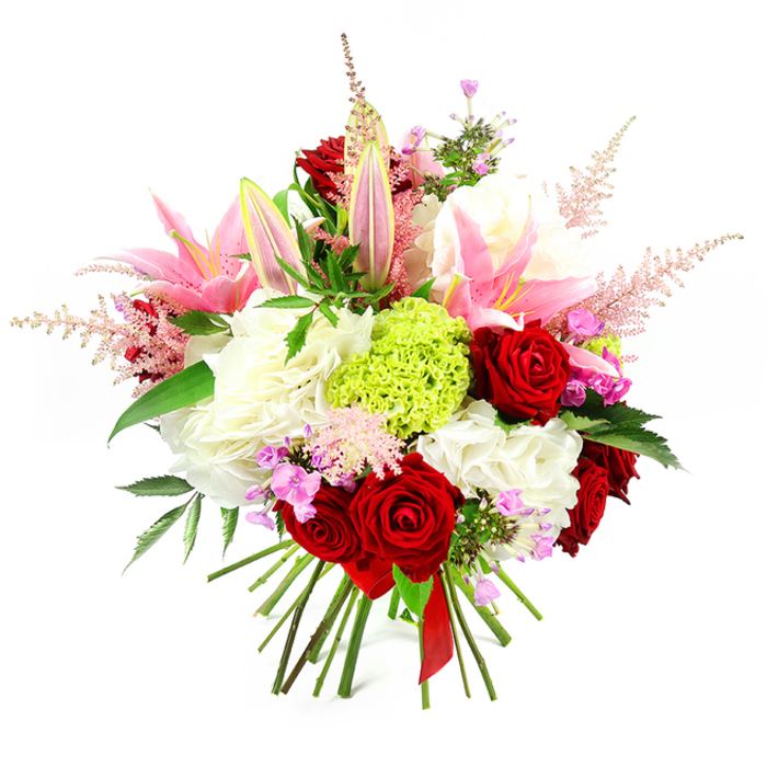 This image shows a luxuriant hand-tied bouquet presented against a pure white background, every flower clearly defined as if freshly arranged on a Clerkenwell workbench. Dominating the composition are sumptuous deep red roses, their velvety petals curled in generous layers that speak of romance and timeless elegance. Interlaced with them, several tall pink lilies rise gracefully, some fully open with broad petals that fade to a softer pink toward the centre, their stamens dusted with pollen, while others remain in slender buds, adding height and a sense of unfolding beauty. The central body of the bouquet is built from plush clusters of white, ruffled blooms-perhaps hydrangeas or full carnations-creating a creamy, voluminous cushion that supports the bolder colours above. Near the middle, an eye-catching orb of lime green dianthus or Green Trick carnation injects a lively burst of colour, its finely textured surface providing a playful contrast to the smoother surrounding petals, much like a contemporary detail amid Clerkenwell's historic architecture. Fine plumes of pale pink astilbe drift outward from the arrangement, giving a feathery, romantic softness and gently breaking the dome shape. Between the main flowers, tiny fuchsia and lavender filler blossoms appear in small clusters, adding hidden pockets of colour and visual interest when viewed up close. Deep green foliage with a subtle sheen peeks from between stems, enhancing the bouquet's depth and framing the brighter tones. At the base, the natural stems are neatly gathered and bound with a deep red satin ribbon, emphasising its hand-tied craftsmanship and readiness for gifting. The overall mood is joyful yet sophisticated, perfect for anniversaries, Valentine's surprises, or elegant dinner parties in Clerkenwell apartments and studios.
