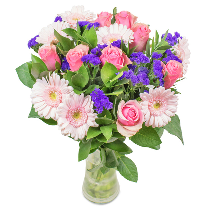 A meticulously arranged bouquet from Clerkenwell Flowers graces a clear glass vase, set against a clean white canvas that lets each bloom shine. At the bouquet's center, 7 to 9 plush, medium-pink roses exhibit their delicate, tightly furled petals, some just beginning to spiral open. These romantic roses are encircled by 5 to 7 pale pink gerbera daisies, their round, layered petals radiating outward from creamy centers, lending a soft luminosity like the glow over Clerkenwell Green on a summer's evening. Vivid clusters of purple statice weave between the larger flowers, lending textural contrast and a pop of royal colour that calls to mind the creativity buzzing through local design studios. Lush, emerald foliage provides depth and abundance, offering a breath of natural freshness reminiscent of nearby Rosebery Avenue. Stems and crystal-clear water are visible in the vase, affirming the bouquet's vitality and making it an inviting gift or centrepiece. This distinct arrangement, available for prompt delivery throughout Clerkenwell, embodies joy, celebration, and heartfelt connection-perfect for birthdays, anniversaries, Mother's Day, or simply adorning a workspace in the creative hub of London.