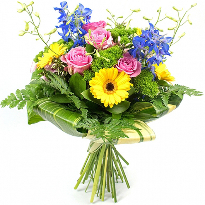 A fresh, professionally arranged bouquet stands upright against a seamless white background, its colours clean and vivid, as though just prepared in a Clerkenwell flower shop before being sent out for local delivery. Dominating the centre are several full, pink roses, their petals layered in gentle spirals that suggest softness and affection, each bloom slightly different, adding a natural, unforced charm. Encircling and intermingling with them are bright yellow gerbera daisies, each flower head a tidy disc of slender petals radiating from a dark brown core, like small suns beaming warmth into the arrangement. Rising from within and just behind the central cluster, tall stems of deep blue delphinium carry multiple petite florets along each spike, introducing vertical structure and a cool, inky contrast reminiscent of evening skies over nearby Clerkenwell Green.   

Around this colourful heart, an assortment of greenery creates depth and balance. Long, feathery fern fronds trail gently from the outer edges, softening the silhouette and adding a slightly wild, garden-inspired feel. Compact clusters of bright green, cushiony filler flowers are tucked between the roses and gerberas, building volume and textural interest without overpowering the main blooms. At the lower portion, broad, glossy leaves-some subtly striped in lighter shades of green-are wrapped artfully around the base of the flower heads, forming a neat, architectural collar that feels modern yet organic. Above the main blooms, a few slender green stems stretch upward, tipped with tiny unopened buds that hint at freshness and new beginnings. The natural stems are visible below, tightly gathered and bound in a pale cream or soft green wrapping material, secured with a simple bow. The overall effect is that of a joyful, contemporary bouquet, perfectly suited to brighten a Clerkenwell apartment, celebrate a work promotion near Farringdon, or bring a splash of colour to a dinner table overlooking St John's Square.