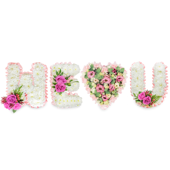 A carefully composed floral statement, photographed on a crisp white plane, spells out H E followed by a full heart and the letter U, creating an intimate, readable message. The letters H, E and U are sculpted from compact white chrysanthemums that form an even, soft surface, their small blooms packed closely to suggest calm and purity. Each letter is trimmed with a narrow blush-pink satin ribbon that ribbons the edges with a subtle pleat, adding a tactile, gentle frame. Floral accents in vivid fuchsia bring life to the composition: two bold roses sit at the base of the H among dark-green ferny leaves and tiny red berries; a central cluster of three fuchsia roses commands attention on the middle bar of the E; and a similar pair of roses decorates the inside lower arc of the U, echoing the arrangement's symmetry. The heart between them is a softer, more romantic panel-layered with pale pink carnations, delicate lisianthus, and cream-toned small roses, punctuated by pale green eucalyptus leaves that create a cool, airy contrast. The mix of textures-the chrysanthemum's plush surface, the satin ribbon's sheen, the roses' satiny petals and the eucalyptus' matte foliage-reads like a conversation between tenderness and strength. The overall effect is both consoling and celebratory, suitable for remembrance or an expressive declaration of love. A local florist might imagine delivering this piece across Clerkenwell, from Leather Lane to Farringdon Road, where its scent and colour would offer comfort and a visible sign of heartfelt devotion.