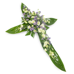 Viewed from a gentle overhead perspective on a plain white backdrop, this floral cross reads as a composed gesture of remembrance, its design anchored by broad, glossy green tropical leaves that form an unmistakable cross silhouette. The leaves, likely Ti or similar waxy foliage, show clear veins and a subtle sheen that catches soft, diffused light, providing a protective foundation for the blooms. Concentrated at the central junction and flowing along each arm, the floral clusters are composed of creamy white lisianthus with their soft, billowing petals, juxtaposed against neat, white daisy-like chrysanthemums that bring compact texture and quiet luminosity. Interspersed throughout are sprays of pale lavender limonium or tiny asters, their starry forms adding a delicate lift of colour and a feeling of gentle breath. Narrow sprigs of fine green filler thread through the arrangement, adding rhythm and a natural, handheld quality. The overall mood is one of tranquil dignity-designed for funeral chapels, memorial services, or graveside tributes-and the balanced tones suggest purity, compassion and hope. As a florist in Clerkenwell I picture this arrangement arriving at St John's Church or a family home near Clerkenwell Green; at Clerkenwell Flowers we assemble crosses like this with attention to proportion, tactile contrasts and the quiet scent of fresh green leaves and soft blooms, and we can advise on delivery to nearby Farringdon and surrounding streets for same-day sympathy needs.