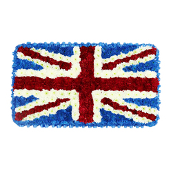 A richly detailed floral Union Jack fills the frame, a rectangular funeral tribute composed entirely of densely packed red, white, and blue blooms. The design is flat in shape yet full of texture, as if a soft tapestry has been woven from petals instead of threads. Deep blue flower heads, clustered closely together, form the background fields and clean outer edge of the piece, giving a strong, steady base to the flag. Across this sea of blue, the wide red St George's Cross stands out with striking clarity, running from top to bottom and side to side, each line firmly defined by bright white floral borders. Diagonal red bands for St Patrick's Cross slice through the flag from corner to corner, with fine white strips separating the red from the surrounding blue and white, faithfully echoing the layered symbolism of the original Union Jack. Every colour block is crafted with meticulous care, so the transitions between red, white, and blue are crisp rather than blurred, reflecting the skill of an experienced florist who understands both design and remembrance work. The flowers themselves appear to be compact chrysanthemums or similar long-lasting varieties, chosen for their durability and intensity of colour, ideal for services and ceremonies across Clerkenwell, Farringdon, and nearby City streets. Set against a simple white backdrop, the arrangement glows quietly, carrying a mood of dignity and reflection. This floral flag would be fitting for a military funeral, a memorial service tied to British heritage, or a commemorative event where family and friends wish to express loyalty, gratitude, and enduring connection to the United Kingdom.
