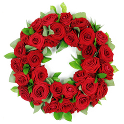 In the soft, patient light of our Clerkenwell studio, I cradle this circular wreath and picture the neighbourhood's quiet corners-the lanes around St John Street, Clerkenwell Green, and the gentle bustle of Exmouth Market. The arrangement gathers dozens of deep red roses into a dense, unbroken ring, their petals velvety and warm as candlelight. Some blooms are just opening, others reveal their layered richness, while subtle variations in crimson create a living shimmer that shifts with the room's glow. Between the roses, sprigs of fresh green foliage-eucalyptus-like leaves, broad and matte, and sharp, glossy ruscus-weave through, adding a cool counterpoint that makes the red feel even more vibrant. The wreath rests in the air with a quiet breath, the white background rendering every contour and texture with crystalline clarity.

This piece is a timeless symbol of eternal connection-careful, intimate, and respectful. It suits funerals, memorial services, anniversaries, or moments when a loved one is being remembered with dignity. In Clerkenwell, we often pair this wreath with a note of personal memory or a short service arrangement, and we can arrange delivery through the day to nearby areas such as Farringdon, Hatton Garden, and the City. Freshness is our promise: stems cut fresh, the wreath assembled to retain life and fragrance as it travels. Clerkenwell Flowers is proud to craft this piece for families across central London, bringing a sense of calm and continuity to hard days.