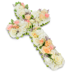 A beautifully detailed floral cross is presented on a clear white background, its form completely covered in fresh, softly coloured blooms that suggest both reverence and gentle farewell. The cross itself has rounded, flowing edges, shaped entirely from a tapestry of roses, hydrangeas and petite filler flowers in white, cream, blush pink and pastel peach, with small accents of lavender. At intervals along the vertical and horizontal arms, clusters of fully opened peach and apricot roses gather together, their ruffled petals adding warmth and a subtle glow. Around them, ivory and pure white roses sit close, their neat rosettes blending seamlessly into domed tufts of white hydrangea that create a plush, quilted effect. Tiny white spray roses and similar small blooms fill every gap, ensuring there is no bare space, so the cross feels solid yet soft, almost like a floral cushion. Threaded lightly throughout are sprigs of pale purple statice or a similar filler, introducing a whisper of colour that brings depth without disturbing the soothing palette. Delicate hints of fresh green foliage emerge from beneath the flowers, tracing the outline and adding natural contrast. The lighting is bright and even, enhancing each tone and texture and casting a faint shadow that gives the cross a sense of presence on the page. This elegant tribute could easily be imagined resting in a quiet Clerkenwell church or a chapel close to Farringdon Road, chosen by local families as a comforting expression of faith, remembrance and gratitude for a life lived with love.