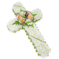 A traditional Christian floral cross is presented on a clean white background, its simple setting allowing the craftsmanship of the flowers to speak for itself. The entire body of the cross is carefully carpeted with countless white chrysanthemums, their tightly packed heads forming a velvety, cushion-like texture that looks almost like freshly fallen snow. This sea of white blooms conveys innocence and serenity, echoing the peaceful stillness of an early morning walk through the quieter lanes of Clerkenwell. Framing the outer edge of the cross, a neat collar of fresh green foliage provides contrast, tracing every curve and angle so the shape reads clearly from top to base. At the central intersection, a beautifully composed spray of roses brings gentle colour and emotion to the tribute. The roses unfold in soft peach, pale pink, and creamy white tones, their petals layered in spirals that suggest tenderness and care. Around them, feathery fern fronds, fine strands of bright green grass, and subtle touches of tiny purple filler flowers add depth and a sense of natural movement, as if a light breeze has just stirred the arrangement. The balance between the pure white foundation and the warm, pastel centre creates a message of hope and remembrance, making this floral cross especially fitting for funerals, memorial masses, and graveside gatherings. It feels like a respectful farewell that could be placed in one of Clerkenwell's historic churches, at a local crematorium chapel, or carried with family and friends as they say their final goodbyes. The design speaks softly, yet with unmistakable love and faith.