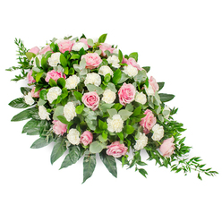 Set against a clean white backdrop, this elongated teardrop funeral spray is arranged with the calm precision of a local Clerkenwell florist, its shape gently curving from a wide, comforting fullness at the upper left into a slender, tapering point at the lower right. The design is dominated by pastel pink roses, their petals unfurling in elegant spirals that range from the palest blush to a richer rose pink, each bloom seeming to cradle a quiet message of love. Interspersed between these roses are generous clusters of soft white carnations, their finely ruffled petals adding both volume and a cloud-like lightness, as if softening the sadness of goodbye. A generous bed of foliage supports the flowers: deep, glossy green leaves give the structure a strong, reassuring presence, while rounded eucalyptus in silvery green threads through the design, introducing a cooler, slightly smoky tone that feels reminiscent of early morning mist along nearby streets like St John Street or Farringdon Road. From the lower edge, slim trails of dark green ruscus and other fine greenery drift outward, creating a gentle cascade that enhances the teardrop silhouette. The overall mood is peaceful and reflective, a sympathetic tribute suitable as a casket spray or to rest beside an urn, offering comfort at a funeral or memorial service in and around Clerkenwell. This arrangement evokes soft fragrance, tender memories, and a sense that love and gratitude continue long after the final farewell.