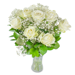 A classically composed hand-tied bouquet of white roses and airy baby's breath, this arrangement centres on roughly twelve pristine roses with soft, creamy petals unfolding at varied stages-some fully open, others in tender bud. Delicate clusters of Gypsophila scatter like fine frost between the larger blooms, creating a luminous halo that breathes lightness into the composition. Glossy green foliage in deep and mid-tones frames the flowers, its rounded leaves providing contrast and structural support so the blossoms sit with calm dignity. The blooms are gathered in a clear glass vase; through it the neatly cut stems and water level are visible, a small but clear sign of freshness and care. Shot against a stark white background, the textures and subtle tonal shifts are emphasised: the roses' satiny surfaces, the baby's breath's feathery dots, the cool sheen of the glass. The overall mood is serene and refined-suitable for a contemplative ceremony, an understated anniversary gift, or a birthday given with quiet affection. Working from our Clerkenwell studio near Exmouth Market, I often prepare similar bouquets for same-day delivery across Clerkenwell and Farringdon, where clients appreciate the thoughtful balance of purity and soft romance. There's a barely-there, clean floral aroma that invites slow breathing and reflection; this is the kind of bouquet that settles a room, offering a gentle, sincere message without shouting, and leaving space for the feelings it intends to express.