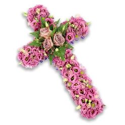 A refined floral cross, designed as a sympathy tribute, appears against a pure white backdrop, its outline defined not by structure but by an unbroken mass of flowers in soft pink, mauve, and lilac tones. The entire cross is layered with fresh lisianthus blossoms, their subtly ruffled petals overlapping like fabric, creating a plush, velvety surface that feels comforting to imagine touching. Shades shift gently from pale blush and light lavender to richer pinks, with many blooms showing darker, almost plum-coloured centers that give a sense of dimension and quiet drama. At the central crossing point, three larger roses in a dusty rose or light mauve hue form a gentle focal cluster, their open, spiralled heads suggesting enduring love and grace. Around these roses, feathery fern fronds and sprigs of bright green foliage peek between the petals, lending contrast and a breath of woodland freshness, reminiscent of the green spaces around Spa Fields or Clerkenwell Green. Scattered throughout the cross are tiny, complementary accent flowers in pink and soft purple, along with pale green buds and small white blossoms that break up the colour and add delicate detail. Along the arms and edges, glimpses of slender dark purple ribbon or fabric appear from under the flowers, subtly strengthening the shape and lending a ceremonial feel. The overall mood is serene and reverent, as though this floral cross were resting at the front of a quiet memorial service in one of Clerkenwell's historic churches, offering silent comfort and a visual prayer of remembrance for a life lovingly honoured.