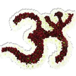 This image captures an ornate Om (Aum) symbol handcrafted from dense, small-headed blooms and set against spotless white. The interior of the symbol is a luxuriant field of dark red-maroon chrysanthemum-style flowers, their tiny lime-green eyes gleaming like secret embers within the rich mass. Encircling and defining the form, a generous ribbon of delicate white spray chrysanthemums outlines every curve, lending a luminous frame that lifts the maroon centre away from the background and accentuates its sacred geometry. The composition casts a soft drop shadow, reinforcing its sculptural presence and the careful elevation of the piece from the white plane beneath.

There's a sensory hush to the arrangement: the velvety density of the burgundy petals suggests a cool, soft touch; the white sprays offer a contrasting crispness under fingertips. A faint, comforting chrysanthemum scent seems implied-subtle and grounding-and the overall palette reads as solemn, devotional and quietly hopeful. Every curve, from the flowing '3' shape to the downward loop and crescent with bindu, is proportioned with exacting floral skill, the packing of blooms chosen to preserve line and volume without gaps.

Seen through a local lens in Clerkenwell, where quiet chapels and meditation groups share space with Exmouth Market's bustle, this piece would sit naturally at a cultural gathering, yoga sanctuary or remembrance service. It honours tradition while showcasing floral craftsmanship, a tactile emblem of peace and spiritual resonance for the neighbourhood and beyond.