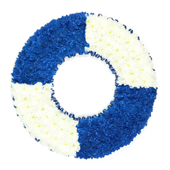 A beautifully composed floral wreath, styled in the unmistakable shape of a lifebuoy, rests against a bright white backdrop so that every petal and ribbon fold is clearly visible. The arrangement forms a perfect circle, its surface made up of hundreds of tiny chrysanthemum-style blooms placed tightly together, giving the ring a plush, cushioned texture. The design is thoughtfully quartered into four bold colour blocks: two opposing sections of rich, royal blue flowers and two opposing sections of cool, clean white. The blue quadrants are saturated and velvety, their intensity suggesting depth and steadfastness, while the white quadrants bring a sense of clarity and peace, softening the overall look. Running neatly around the inner edge of the ring is a slim band of dark blue ribbon, gently ruffled, which accentuates the hollow centre and enhances the seaside, harbour-side feel you might associate with river walks from Clerkenwell down towards the Embankment. There are no visible stems or foliage; instead, the focus remains purely on colour, form, and symbolism. The lifebuoy shape evokes ideas of protection, rescue, and safe passage, making this an especially poignant funeral tribute for someone connected to sailing, maritime service, or simply remembered for their reliability and care. Crafted with the attention to detail you would expect from experienced Clerkenwell florists, the arrangement feels both contemporary and timeless, ideal for memorial services, cremations, or wakes held around local churches and chapels, where a strong yet understated floral statement of remembrance is desired.