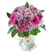 Elegant and vibrant, this mixed bouquet presents a harmonious blend of soft lavender roses, lively fuchsia Gerbera daisies, and clustered plum chrysanthemums, all gathered in a rounded arrangement brimming with life. The delicate interplay of pinks and purples is contrasted beautifully by airy white gypsophila, whose feathery blooms evoke the gentle light that streams into Clerkenwell's artisan lofts. The stems are gathered tightly and anchored in a compact clear glass vase with a subtly crackled surface, its artisanal touch echoing the neighbourhood's rich tradition of craft. Lush, dark green leaves add structure, emphasis, and a burst of natural freshness. Around the vase's neck, a piece of rustic raffia is tied, suspending a cheerful birthday tag with artistic red and green lettering and a petite floral motif. The entire arrangement, thoughtfully composed by local Clerkenwell florists, radiates warmth and sophistication-delivering both joy and artistry to any celebration, whether marking a birthday, anniversary, or simply sending heartfelt wishes within this creative corner of London.