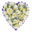 A heart-shaped floral tribute composed entirely of soft whites and creams rests against a clean white backdrop, its form gently defined by careful, layered composition. At the center sits a single, creamy-white rose with tightly spiralled petals that read like a quiet heartbeat; around it a plush field of white carnations provides volume and a velvet softness, their ruffled edges catching the light. Scattered among the fuller blooms are pure white chrysanthemums and spider-like mums whose spiky petals and pale green centers add a bright, delicate texture, while clusters of miniature cream roses and budding lisianthus offer small, intimate points of interest. Blue-green eucalyptus leaves thread through the composition, their silvery sheen and cool scent giving a muted contrast that keeps the palette rooted in nature. The entire heart is edged with a ruffled deep purple ribbon, scalloped along the perimeter to frame the flowers with a dignified, solemn accent that reads both elegant and respectful. Soft studio lighting highlights the layered petals and the subtle shadows between blooms, suggesting a hush of fragrance and a tactile softness underhand - the feel of petals against palms. This cushion-style spray carries a tone of peaceful remembrance and composed grief, a floral language suited to funeral services or memorials. In Clerkenwell, where local families sometimes choose simple tributes for St James' services or nearby gatherings, this design communicates enduring love and quiet dignity, offering a gentle visual presence that comforts without ornamentation.