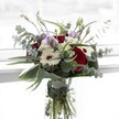 Designed for moments of gratitude and gentle celebration, this captivating bouquet draws together the elegance of Clerkenwell's urban landscape. Dominant, rich red roses blossom at the centre-each one plush and evocative-surrounded by stately white gerberas with their striking brown eyes, reminiscent of the contrast found in the district's modern-meets-classic architecture. Wisps of lavender lisianthus add a breath of dusk-like colour, mingling with clusters of soft white chrysanthemums nestled between. The bouquet radiates energy, thanks to arches of eucalyptus that stretch outward, their silvery discs glimmering in changing daylight much like foliage glimpsed in Spa Fields Park. Bold, structured green leaves cradle the arrangement, providing support and a sculptural finish. Through the vase's crystal clarity, vibrant green stems are visible, underscoring the freshness synonymous with Clerkenwell Flowers' same-day service. Softly fragrant with notes of rose and eucalyptus, this bouquet conjures a sense of tranquil optimism-ideal for new beginnings, thoughtful appreciation, or simply marking an everyday moment in the lively community of Clerkenwell, where each stem is chosen to cradle beauty and connection.