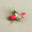 A single-stem boutonniere lies diagonally across a softly textured, light beige fabric, its linen-like weave giving a gentle, natural backdrop that lets every detail of the flowers shine. At the heart of the design is a tightly furled rosebud in rich fuchsia pink, the petals smooth and velvety, catching the light so that the deeper magenta shadows curve into brighter, almost raspberry highlights along the edges. Clusters of tiny white baby's breath nestle around the rose, their cloud-like blossoms adding a delicate, airy halo that softens the strong colour of the central bloom. Fine, feathery sprigs of bright green foliage, reminiscent of asparagus fern or ruscus, fan out from behind the rose, their slender fronds creating a sense of movement, as if a soft Clerkenwell breeze had just brushed through the arrangement. Broader, deeper green leaves sit closer to the stem, grounding the composition and adding structure beneath the more whimsical greens. The stems are neatly gathered and wrapped with a thin, glossy red satin ribbon, its sheen catching the light in small glints and forming a neat, compact band that secures the boutonniere in a tidy column. The simple elegance of the ribbon echoes the rose's romantic hue, making this a timeless lapel flower for weddings and proms around Clerkenwell Green, Exmouth Market, or a smart registry office ceremony. The bright, even lighting in the image reveals every texture-from the plush rose petals to the slightly rough fabric beneath-conveying a feeling of freshness, care, and quiet anticipation, as if the boutonniere is waiting to be pinned on just before a meaningful, celebratory moment begins.