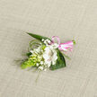 A delicate floral corsage is displayed on a pale oatmeal-toned woven fabric, the soft, nubby texture beneath it enhancing the sense of hand-crafted care. The focal flower is a white alstroemeria-like bloom, fully open, with creamy petals that gently curl back to expose fine reddish-brown speckles and stripes along the throat, giving the blossom both character and depth. Clustered beside it are smaller white buds and half-open flowers, their petals still tightly wrapped, suggesting freshness and anticipation, while airy twigs of baby's breath thread through the design like tiny scattered stars. To one side rises an elongated, bright green cone of Ornithogalum buds, each bud closely nestled against the next, creating a striking vertical accent that feels almost architectural. Dark green leaves form a protective cradle around the flowers, their smooth, slightly curved surfaces contrasting with the feathery tips of slender grass-like foliage that arc and loop around the edges. At the base, a narrow pink satin ribbon is wrapped firmly around the stems and finished with a tidy little bow, its cheerful colour echoing the joy of a celebration in Clerkenwell, perhaps for a registry office wedding near Farringdon or a chic gathering in a local townhouse. The natural, diffused lighting highlights the crisp whites and lively greens, capturing the sense of purity, calm, and quiet excitement that often accompanies a special milestone. This petite floral piece feels ideal for pinning to a lapel or fastening at the wrist, a small yet significant touch for weddings, formal dances, or intimate celebrations across the EC1 neighbourhood.
