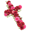 This image shows a traditional floral cross arranged as a thoughtful funeral tribute, resting against a bright white background that makes every colour stand out clearly. The cross is completely covered in roses, with no gaps, giving it a plush, almost sculpted appearance. Deep crimson red roses form the backbone of the design, running along the upright and crossbar with luxuriant, velvety petals that curl in tight, elegant spirals. Threaded among them are fuchsia pink garden roses, their lively tone bringing a tender glow and gentle contrast, suggesting affection, remembrance, and the many joyful moments shared with the departed. Tucked between the open roses are small rosebuds in matching red and pink, adding subtle height, texture, and a feeling of life still unfolding. The outer edge of the cross is carefully finished with a narrow border of petite white blooms, likely spray chrysanthemums or dainty carnations, which create a light, cloud-like trim that frames the cross and emphasizes its sacred form. Delicate hints of green leaves and perhaps fine ribbon strands peep out at the perimeter, grounding the vivid colours in soft natural tones. The lighting is even and calm, showing each petal and contour in clear detail, so the arrangement feels serene and composed. Ideal for a church or crematorium service around Clerkenwell and nearby Farringdon, this floral cross would sit beautifully beside a coffin or memorial photograph, offering quiet comfort and a dignified symbol of faith and enduring love.