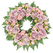 In this image, a serene floral wreath is pictured from above, resting on a clean white background that frames its circular form with clarity and simplicity. The wreath is densely woven with large, open roses in dusty lavender, antique mauve, and soft grey-purple, each bloom displaying layers of velvety petals that curl inward and overlap, creating a sense of depth and quiet richness. Tucked between these feature roses are sprays of smaller blush pink roses and rosebuds, some just beginning to open, their lighter colour adding a touch of warmth and tenderness to the more subdued mauve tones. The entire ring is underpinned by a lush bed of dark green ferns, their finely cut, feathered fronds extending slightly beyond the flowers to create a deep, textured frame that contrasts beautifully with the soft pastels above. Tiny accents of darker greenery and small, shadowy buds are scattered discreetly through the design, preventing it from feeling flat and giving the impression of a natural, hand-crafted piece rather than something overly formal. The wreath's symmetry and unbroken circle speak of continuity, remembrance, and love that endures, an echo of the calm spaces around Clerkenwell's churchyards and gardens. Even, gentle lighting brings out the true colours of the roses and the sheen of the foliage, enhancing the sense of craftsmanship. The overall impression is of a dignified sympathy wreath, suitable for a funeral, memorial service, or quiet tribute at home, offering comfort and condolence through understated, elegant beauty.