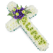 A carefully arranged floral cross rests against a white background, designed as a graceful sympathy tribute for a funeral or memorial in Clerkenwell. The cross is fully covered with tightly massed white spray chrysanthemums, their small rounded heads forming a smooth, cushion-like surface that suggests purity, peace, and a soft place for the eye to rest. Around every edge of the cross, a crisp band of bright green ribbon or foliage runs in an unbroken line, clearly defining the arms and length of the piece so that its Christian shape stands out in clear relief. Along the centre of the vertical arm, a panel of lime-green button chrysanthemums draws the eye downwards, adding gentle contrast and a feeling of fresh new growth among the white. Fine, almost gossamer-thin pale green wires are arranged in a subtle criss-cross pattern over this central strip, adding a refined, contemporary detail that hints at the florist's steady hands and attention to craftsmanship. At the cross's heart, where the arms meet, a rich focal arrangement of deep purple lisianthus blooms is nestled among lime-green button mums, their velvety petals and bright centres creating an expressive burst of colour. Behind and around this cluster, dark green fern fronds and smaller leaves arc outward, creating depth and a sense of natural movement, as if a small garden has grown at the centre of the cross. The overall design feels calm and reverent, well suited to a church or chapel setting in Clerkenwell, offering a thoughtful way to honour faith, remembrance, and enduring love.