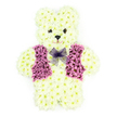 A lovingly designed floral teddy bear sits alone against a bright white background, its form sculpted with the precision of an experienced Clerkenwell florist. Every part of the bear - rounded head, stout body, short arms, and little feet - is densely covered with creamy white chrysanthemum blooms, placed so closely that they resemble a coat of soft, plush fur. The petals vary subtly in shade from ivory to pale cream, giving depth and natural movement to the surface, like light brushing over fabric. Two dark, rounded flower centres serve as the teddy's eyes, creating a gentle, almost watchful gaze, while a smaller dark bloom marks the nose, with surrounding petals arranged to hint at a tiny, tender smile. The chest is dressed in a smart vest of purple and mauve flowers, carefully positioned to form a neat V-shape and distinct lapels, lending the bear a sense of personality and respectfulness. Around the neck sits a translucent lavender mesh bow, its loops and tails resting lightly on the floral fur, adding an elegant finishing touch. The simple white backdrop keeps all attention on the tribute itself, highlighting the freshness of the blooms and the balance of cream and purple tones. One can almost sense the faint, green fragrance of cut stems, reminiscent of early-morning flower deliveries heading out from nearby Clerkenwell studios. This floral teddy bear is an especially moving choice for children's funerals and memorials, offering a visual embodiment of innocence, comfort, and enduring affection.